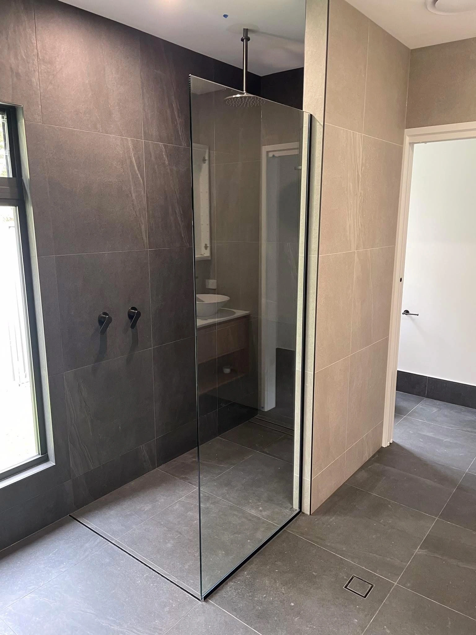 Frameless glass shower screen fitted in a bright Sunshine Coast bathroom